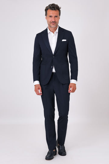 Navy blue suit on a model, front view with patch-pocket jacket and matching trousers