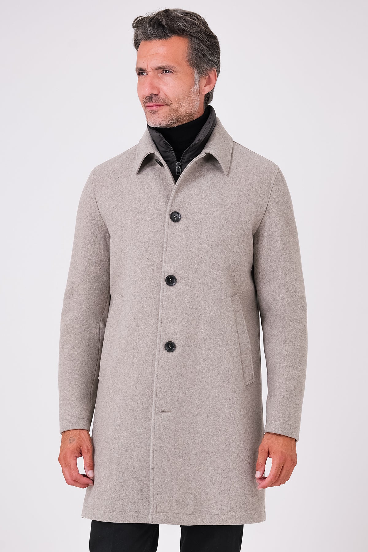Cappotto beige con pettorina interna e chiusura a bottoni, indossato, vista frontale