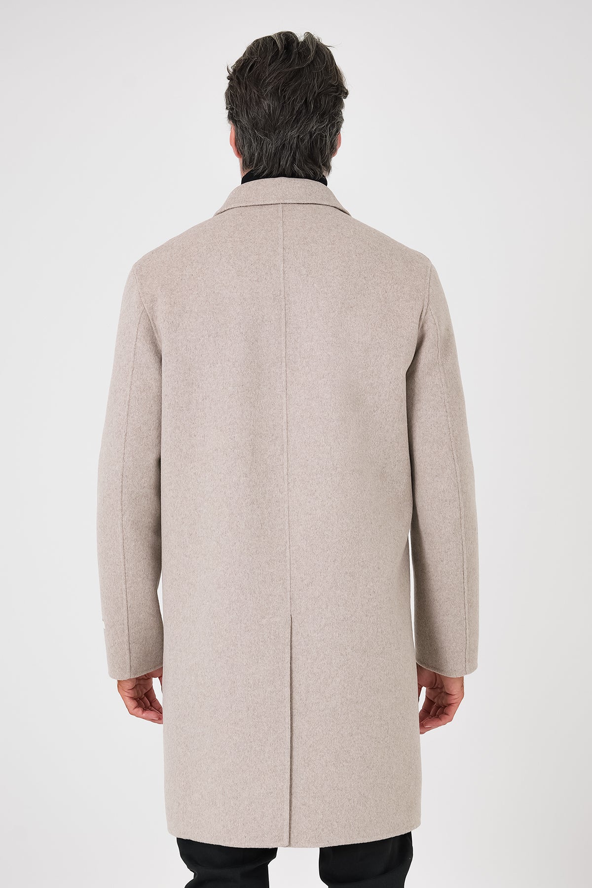 Rear view of the beige coat on a model with a centre vent