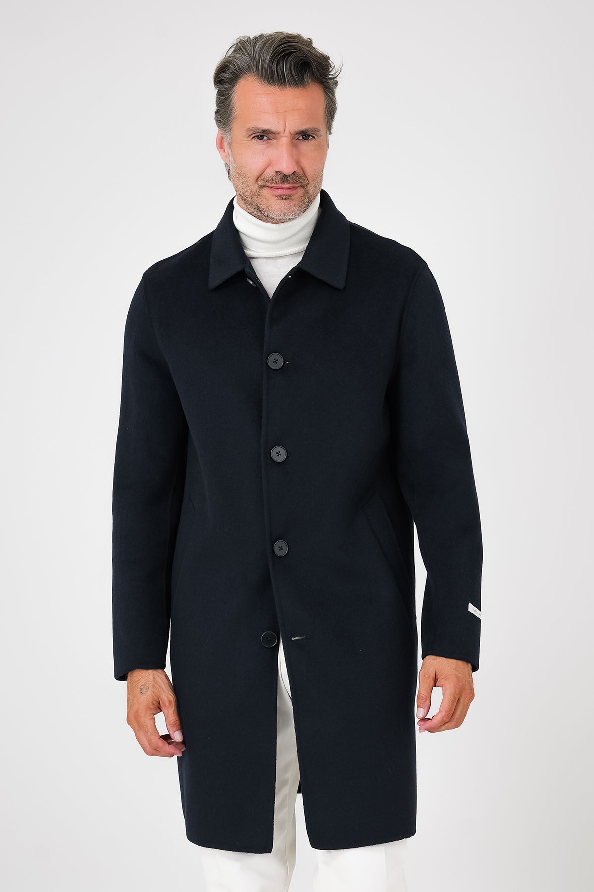 Front view of navy blue coat with shirt collar and visible buttons on a model