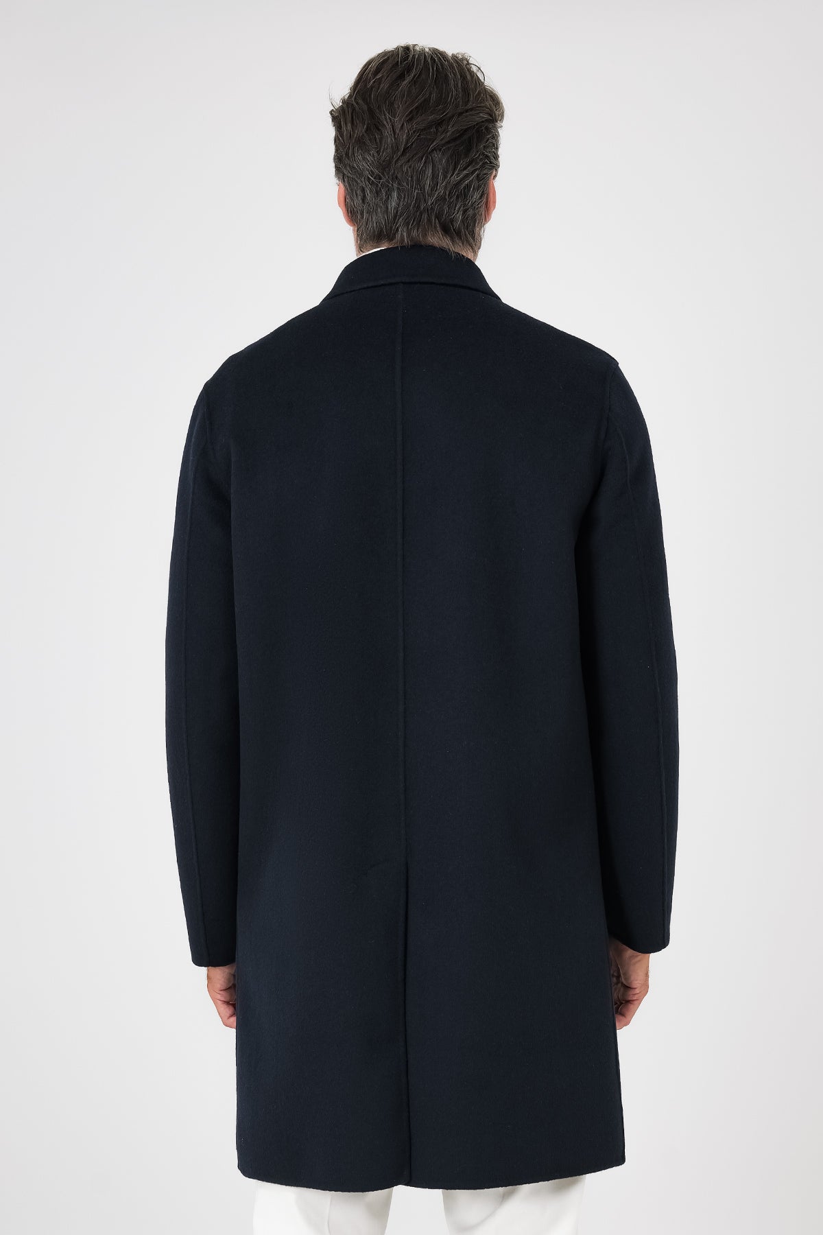 Rear view of the navy blue double-faced coat on a model, with a centre vent