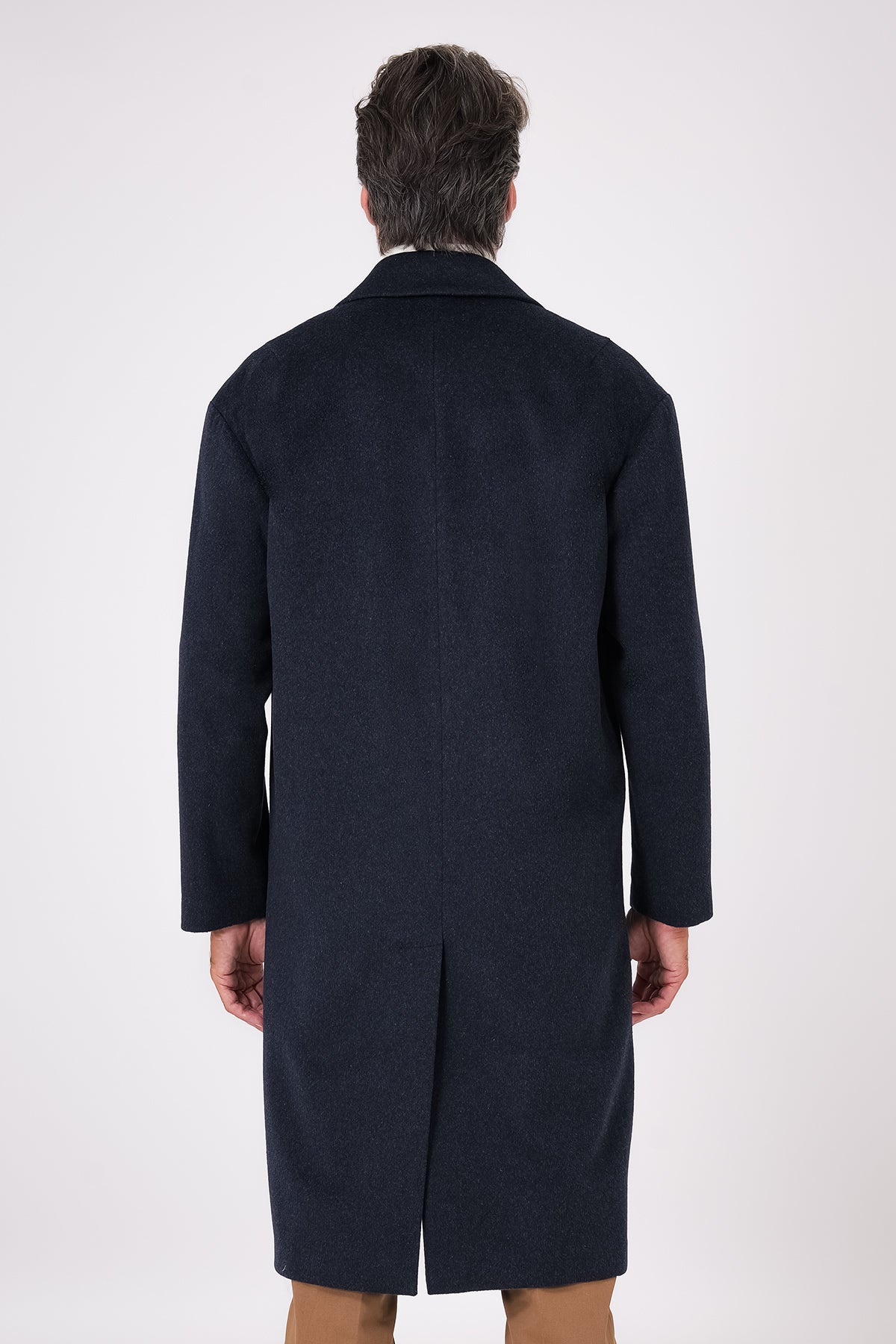 Rear view of navy blue oversized coat with dropped armholes and centre vent on a model