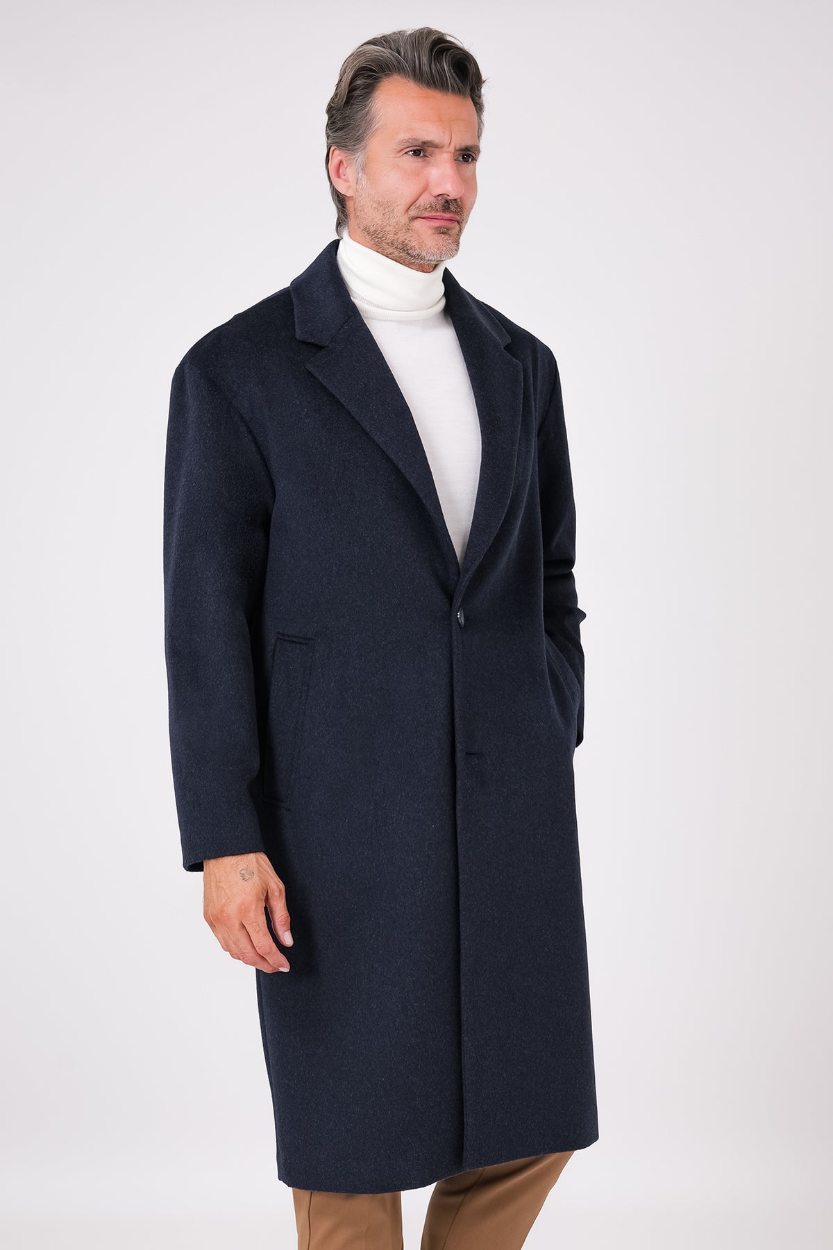 Front view of an oversized navy blue coat with dropped armholes and lapels, on a model