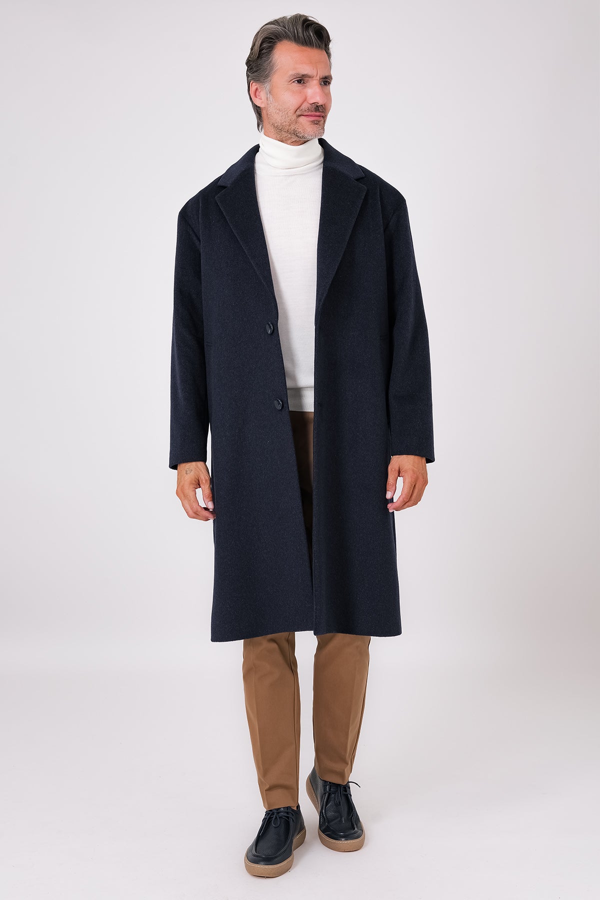 Front view of an oversized navy blue coat with lapels and dropped armholes on a model