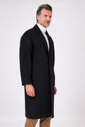 Side view of the black oversized coat with dropped armholes on a model