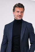 Blue herringbone jacket on a model over a roll neck, front view