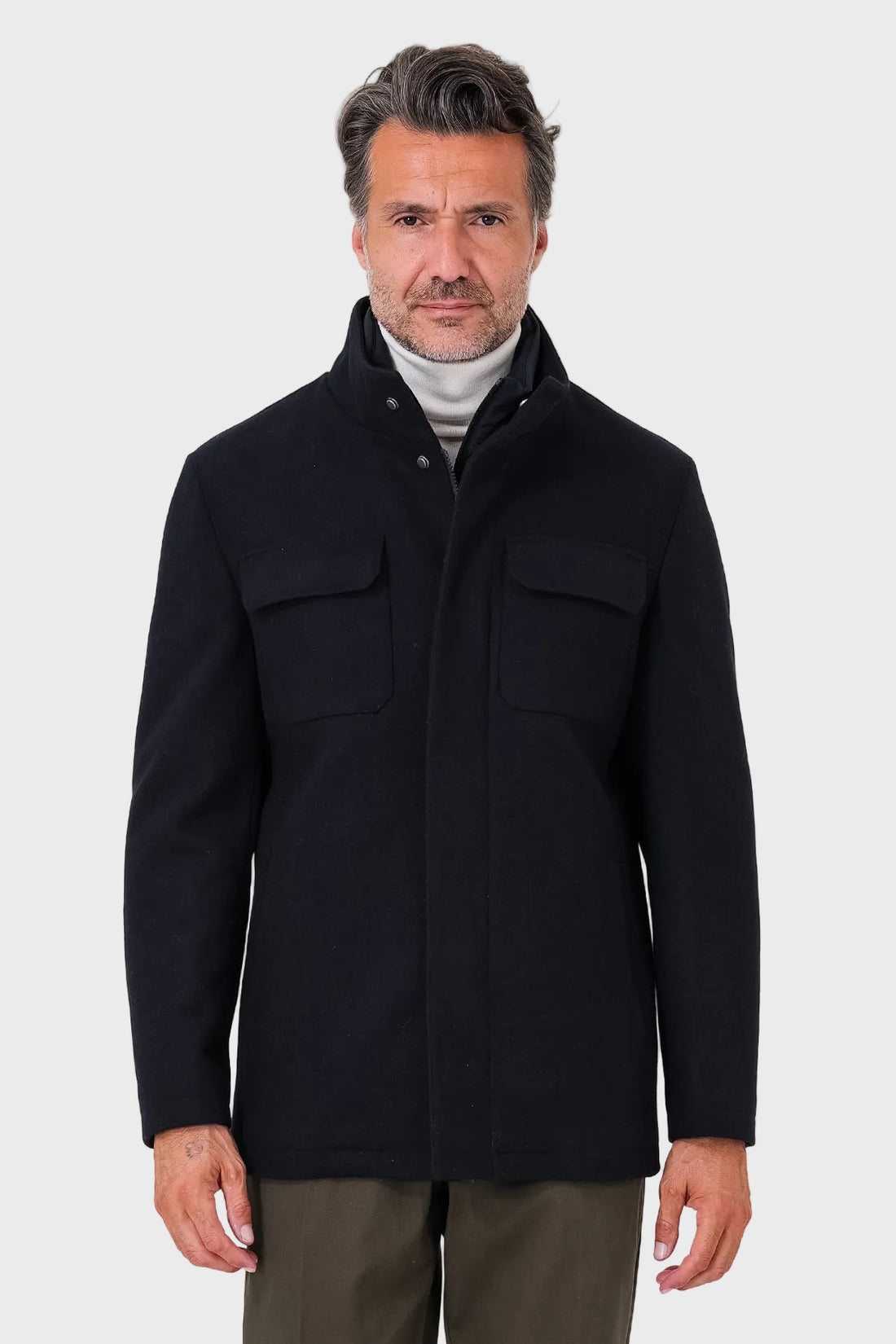 Vista frontale di un giaccone blu navy indossato, con collo alto e tasche con patta sul petto