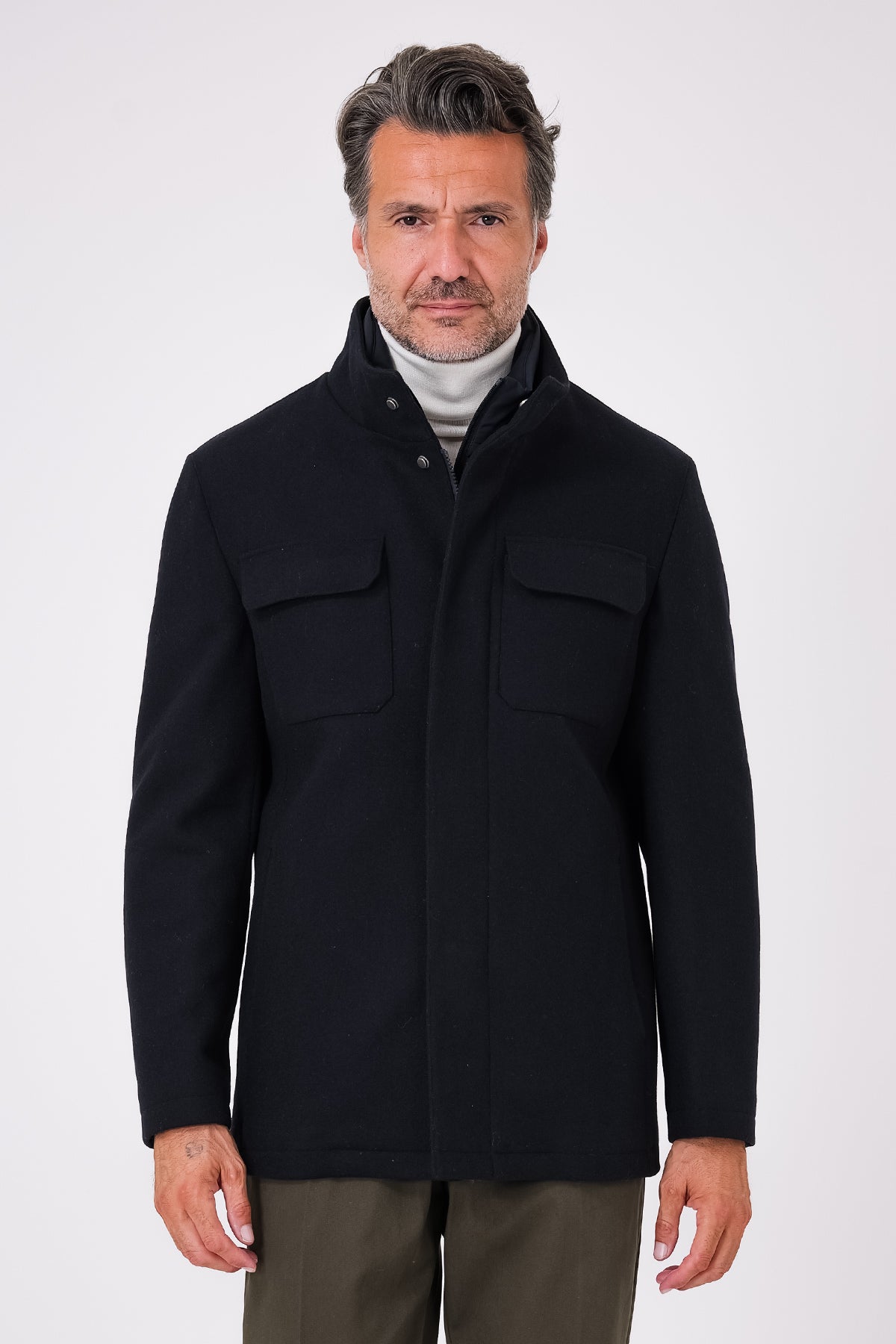 Vista frontale di un giaccone blu navy indossato, con collo alto e tasche con patta sul petto