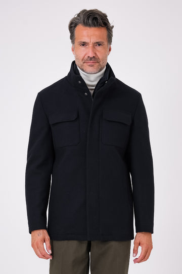 Vista frontale di un giaccone blu navy indossato, con collo alto e tasche con patta sul petto
