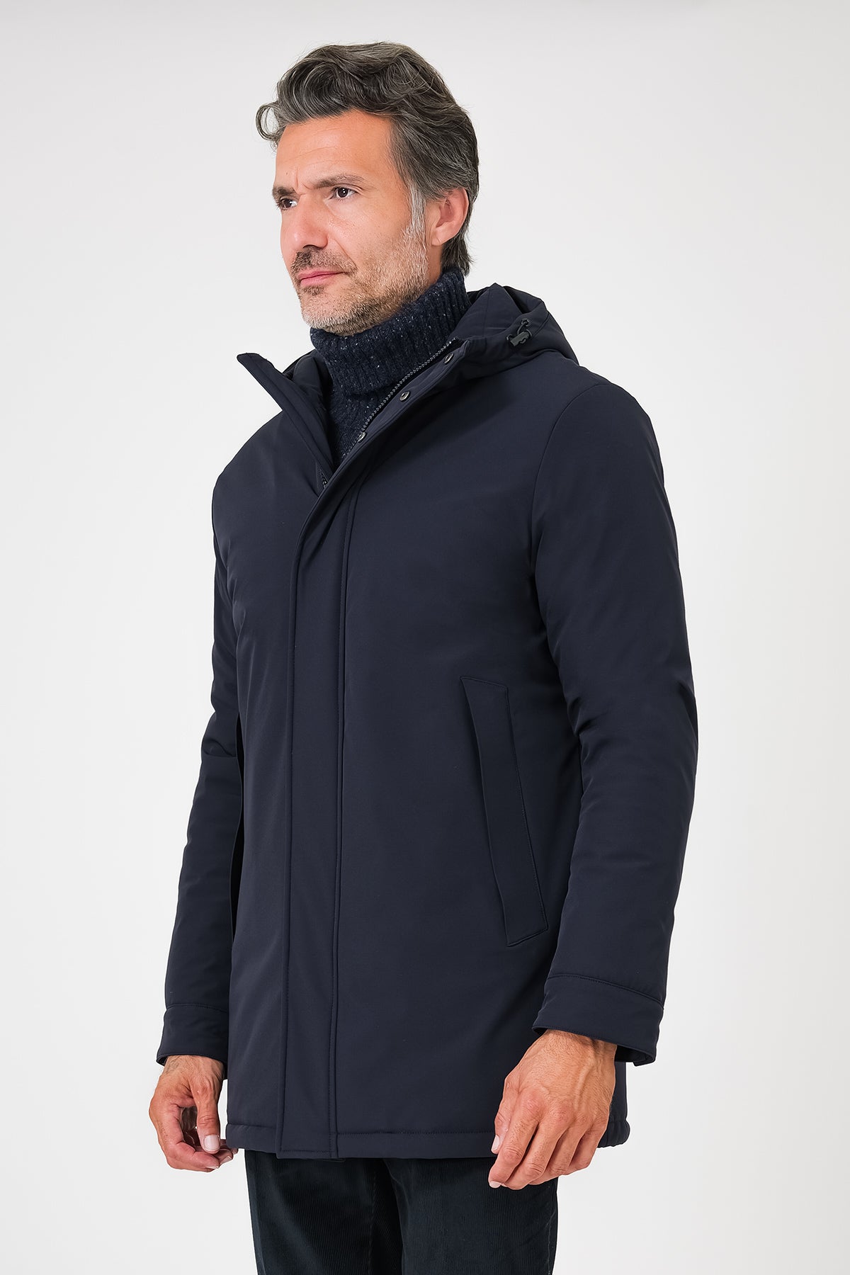Giaccone tecnico con cappuccio blu navy indossato, vista frontale a tre quarti