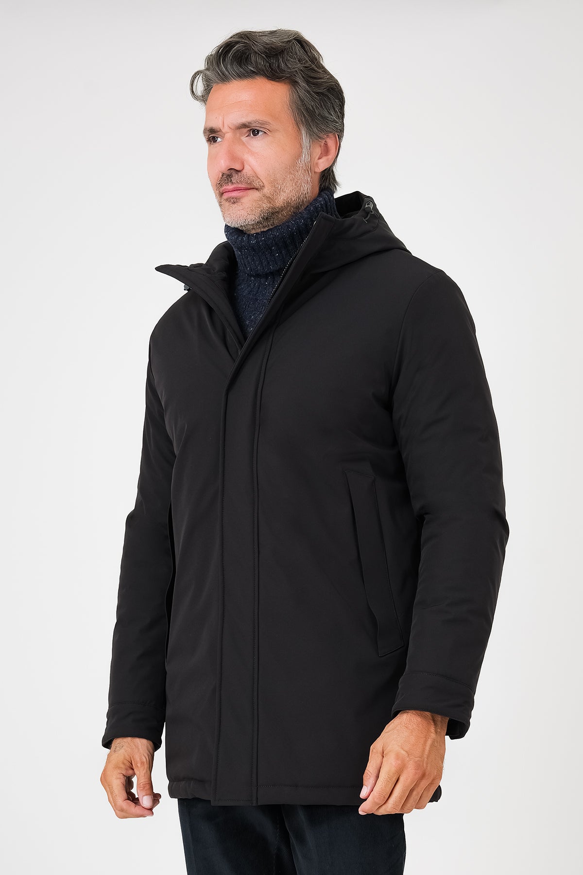 Giaccone tecnico nero con cappuccio indossato da modello, vista frontale a tre quarti