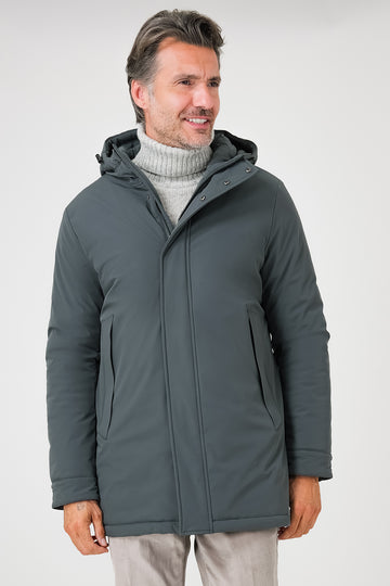 Vista frontale del giaccone tecnico verde con cappuccio e tasche laterali indossato da un modello