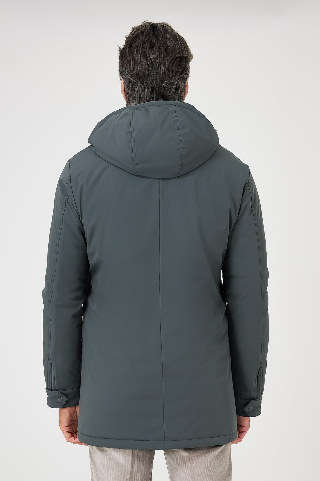 Vista frontale del giaccone tecnico verde con cappuccio e tasche laterali indossato da un modello