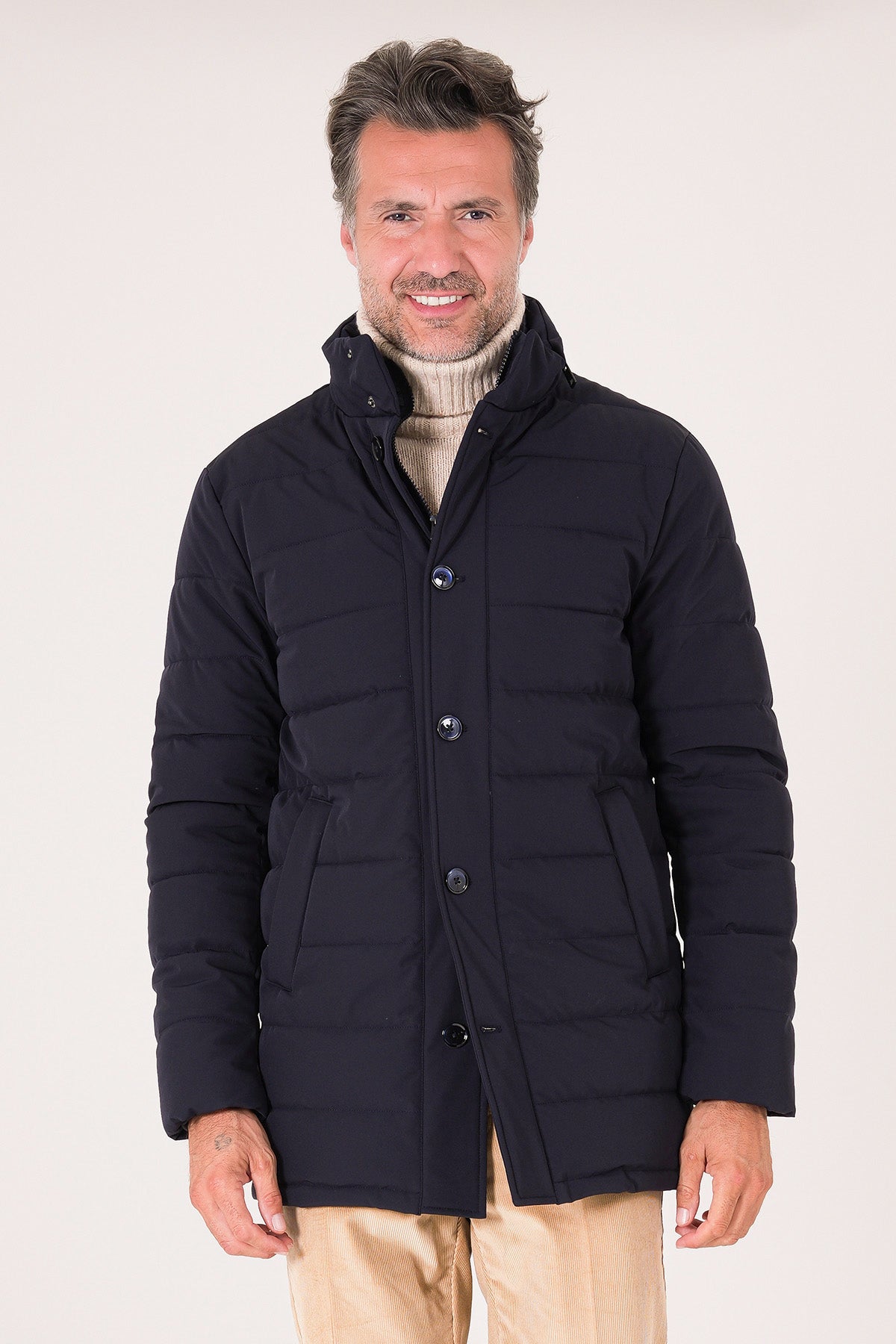 Vista frontale del giaccone tecnico trapuntato blu navy indossato con collo alto e chiusura a bottoni
