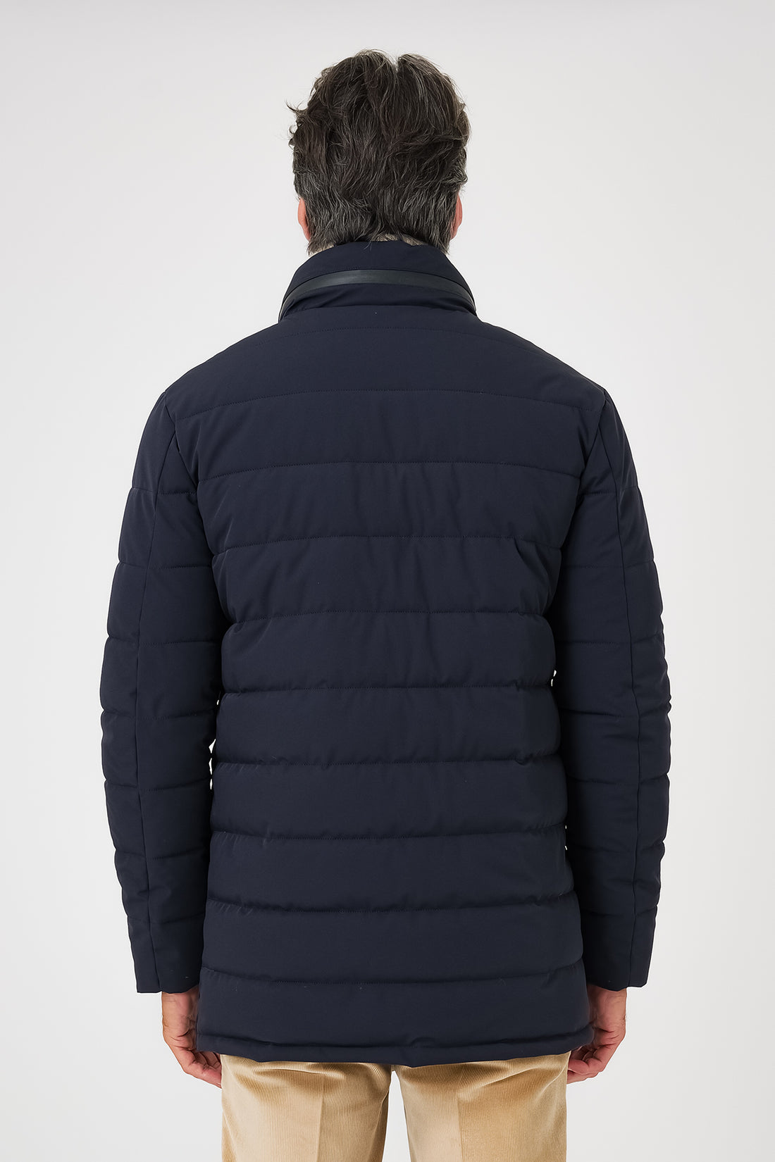 Vista frontale del giaccone tecnico trapuntato blu navy indossato con collo alto e chiusura a bottoni