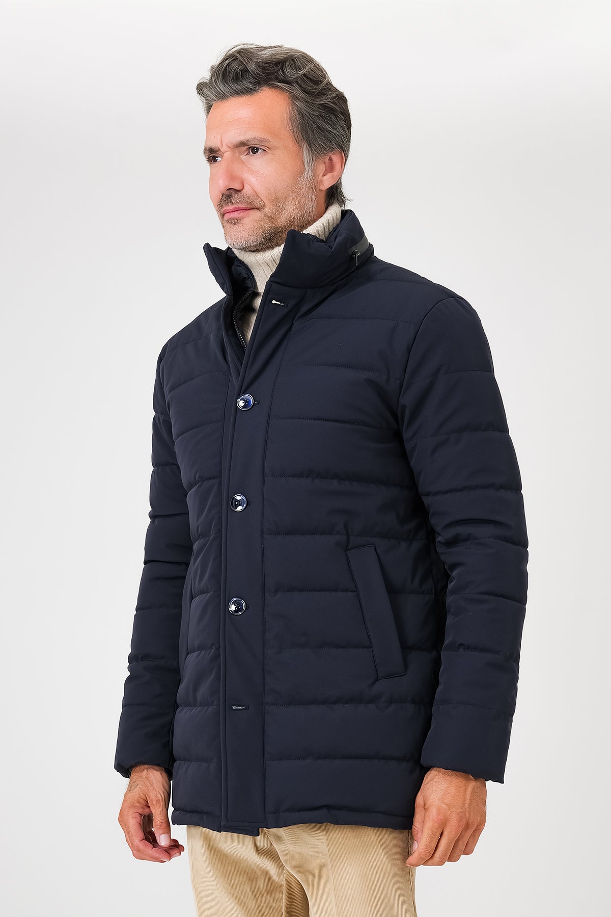 Giaccone trapuntato blu navy indossato, con collo alto e tasche inclinate visto dal davanti