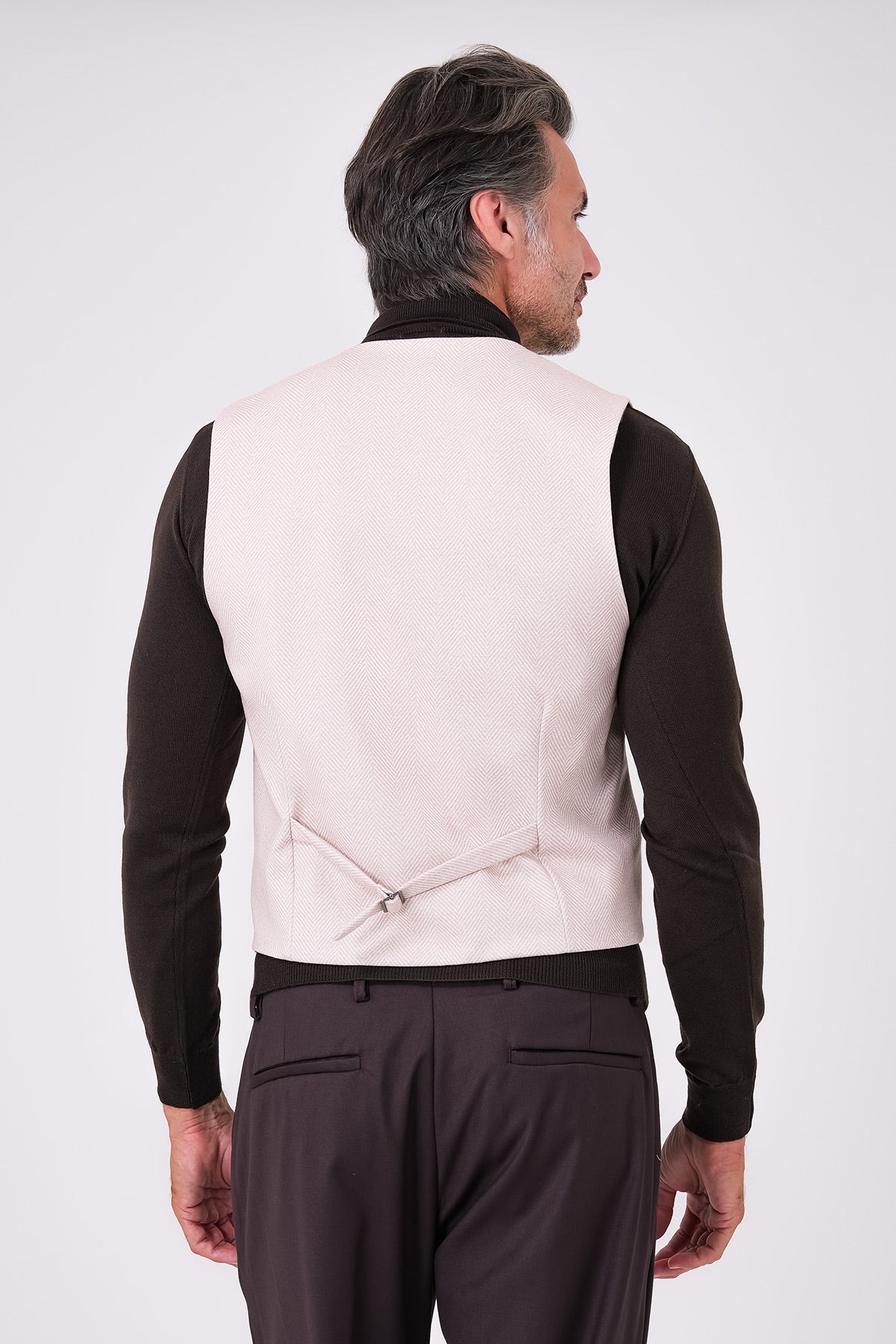 Rear view of beige herringbone waistcoat on a model, with an adjustable back strap