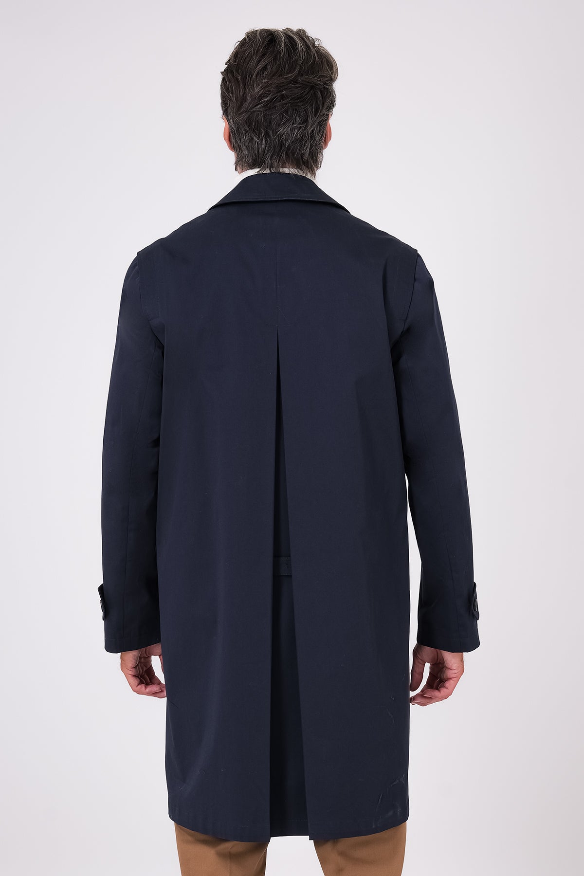 Vista posteriore dell'impermeabile blu navy indossato, con piegone centrale sul retro