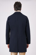 Back view of the navy blue raincoat on a model with a centre vent