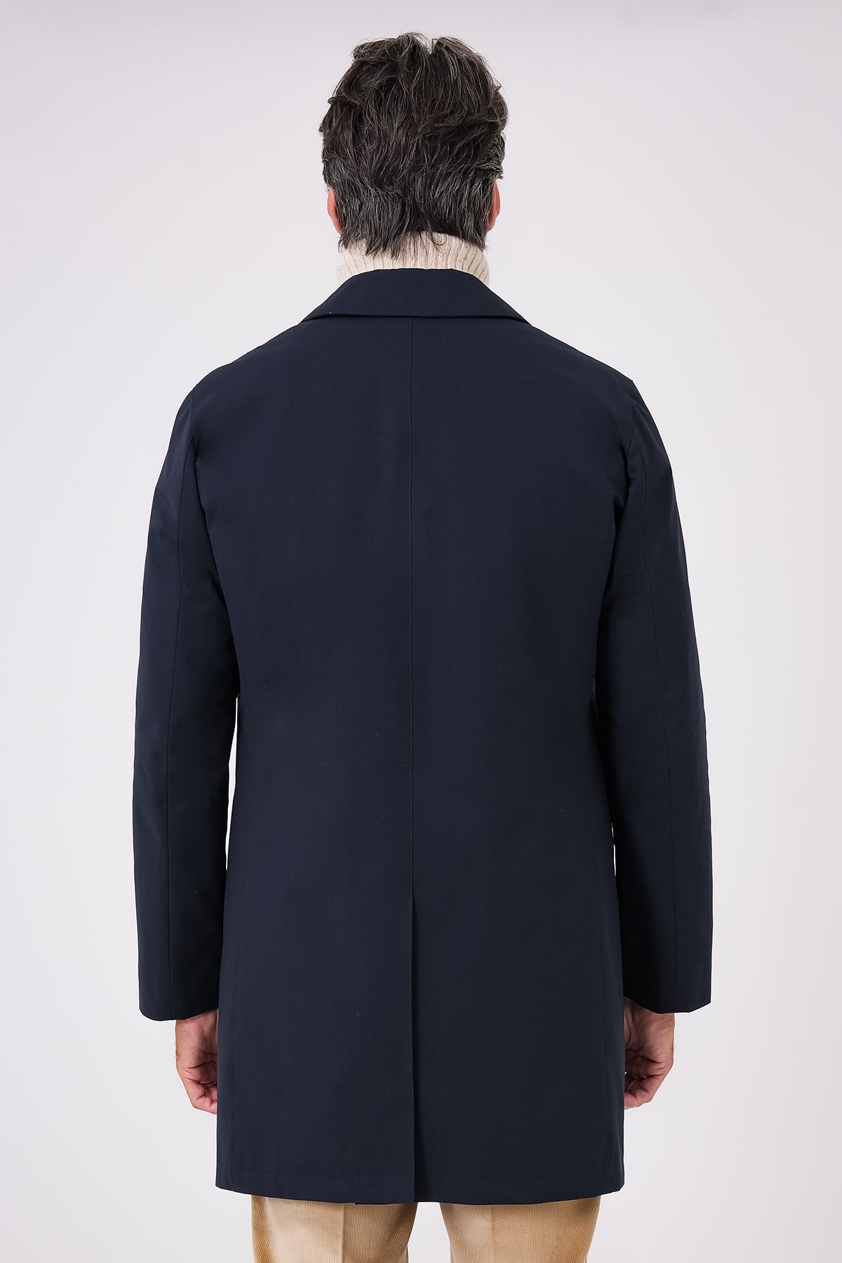 Back view of the navy blue raincoat on a model with a centre vent