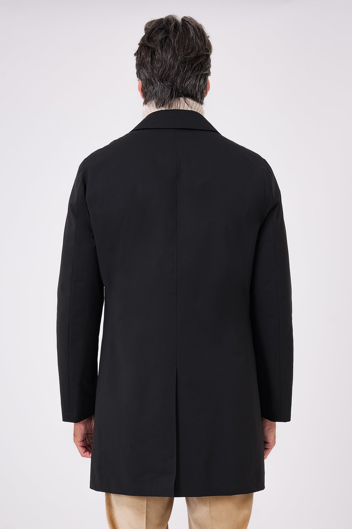 Rear view of the black raincoat with a centre vent, on a model