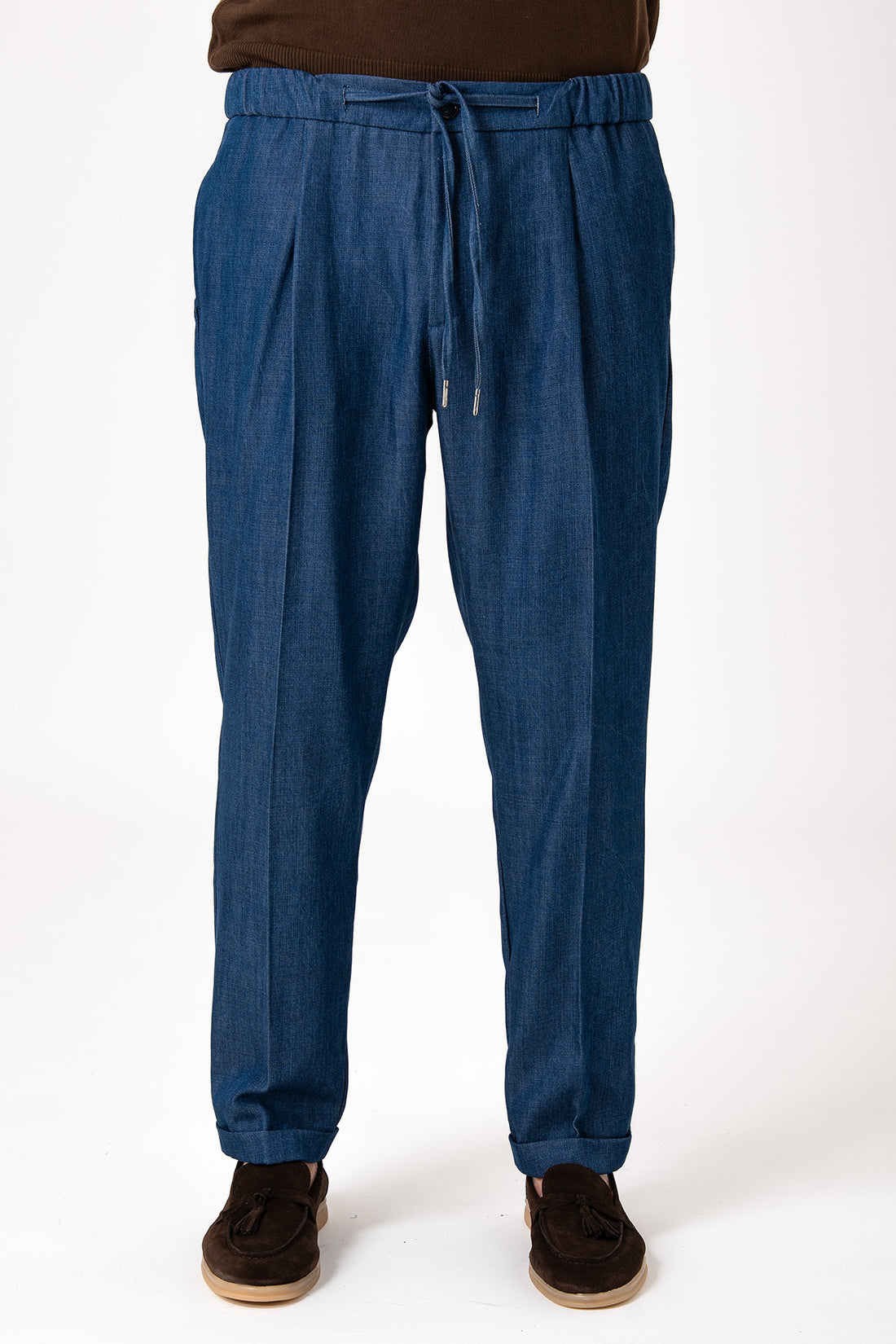 Man wearing a pair of dark blue jeans with central laces and cuffs, front view