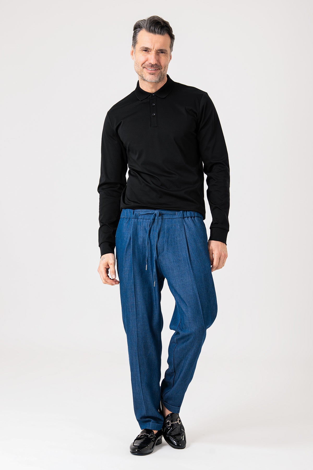 Man wearing blue denim jeans with drawstring and cuffs front view