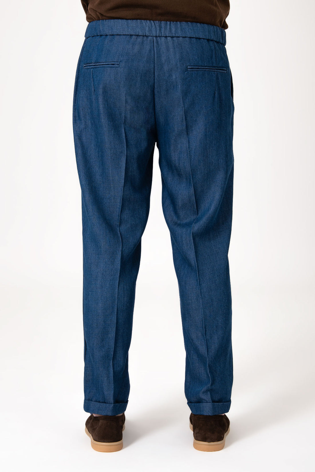 Man wearing a pair of dark blue jeans with central laces and cuffs, front view