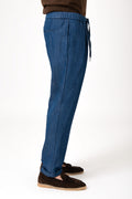 Person wearing denim jeans with drawstring waist and cuffed hem side view