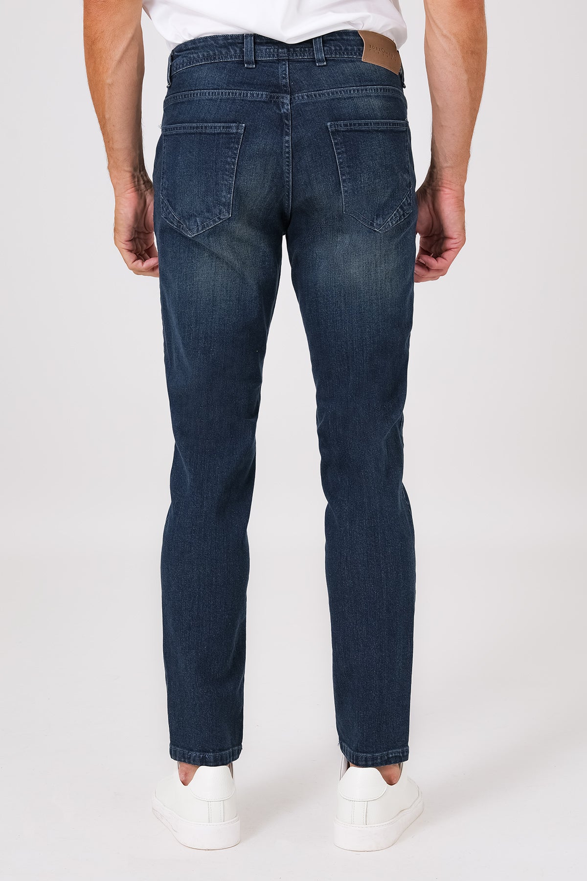 Vista posteriore dei jeans in denim medio indossati, con tasche sagomate e salpa in vita