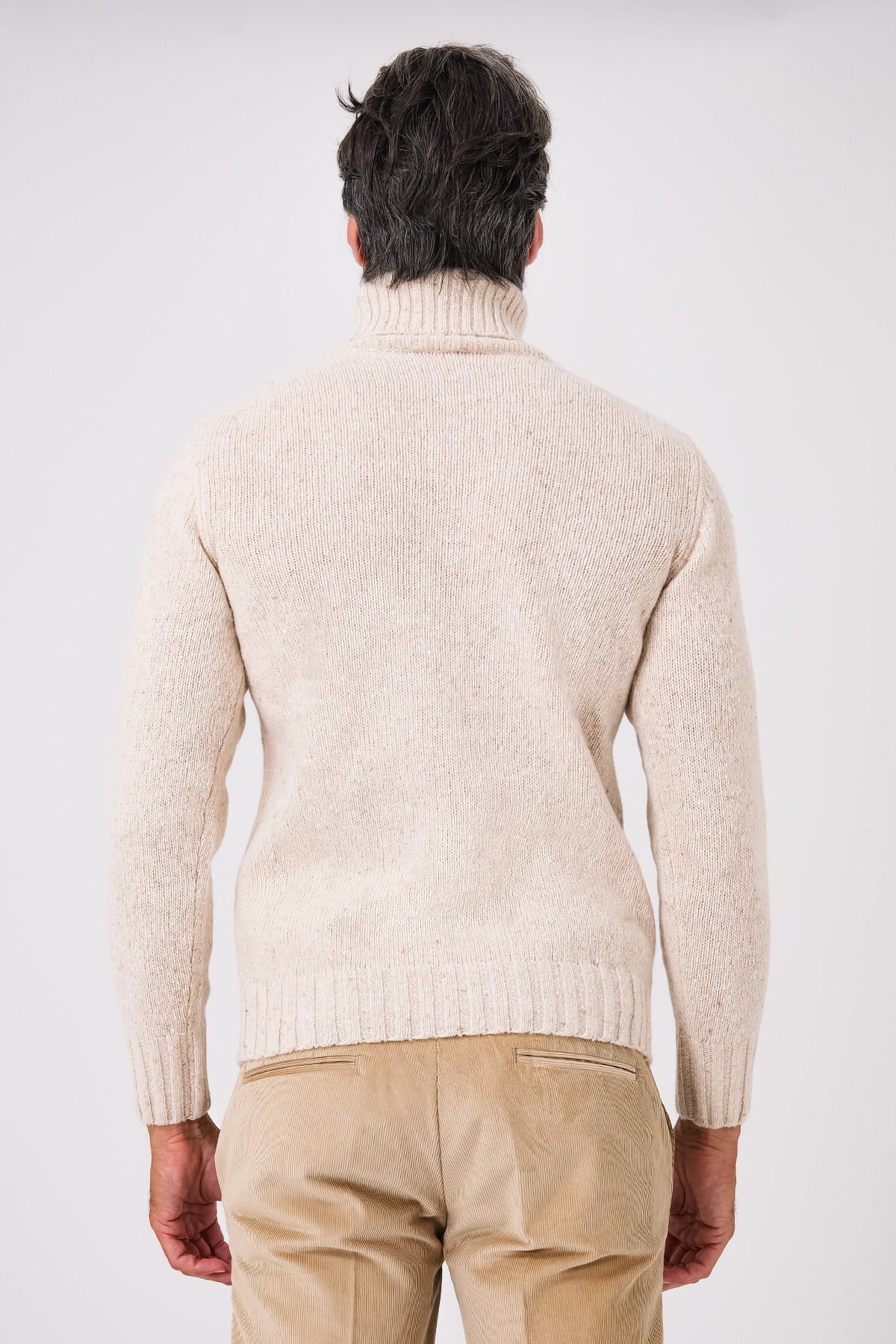 Vista posteriore della maglia dolcevita beige in misto lana indossata