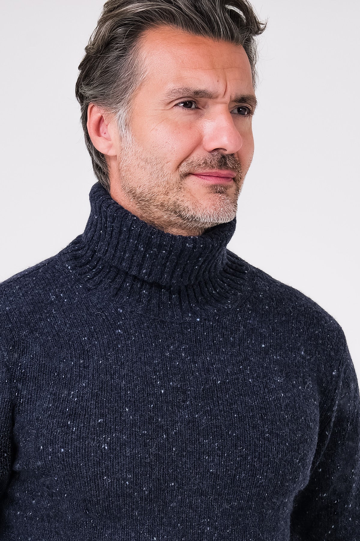 Dettaglio del collo alto a costine della maglia dolcevita blu navy in misto lana indossata