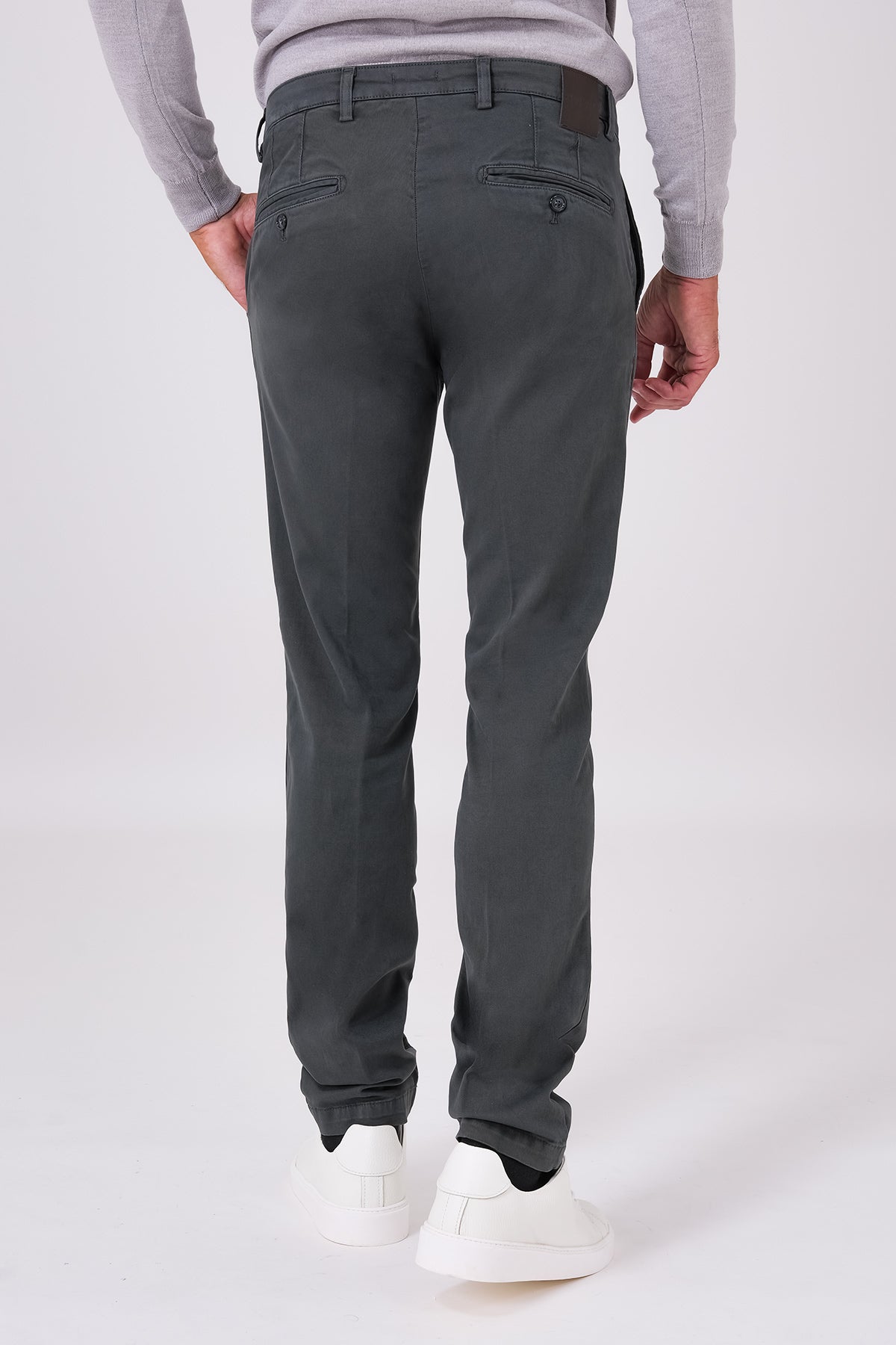 Back view of smoke grey trousers on a model, with buttoned welt pockets