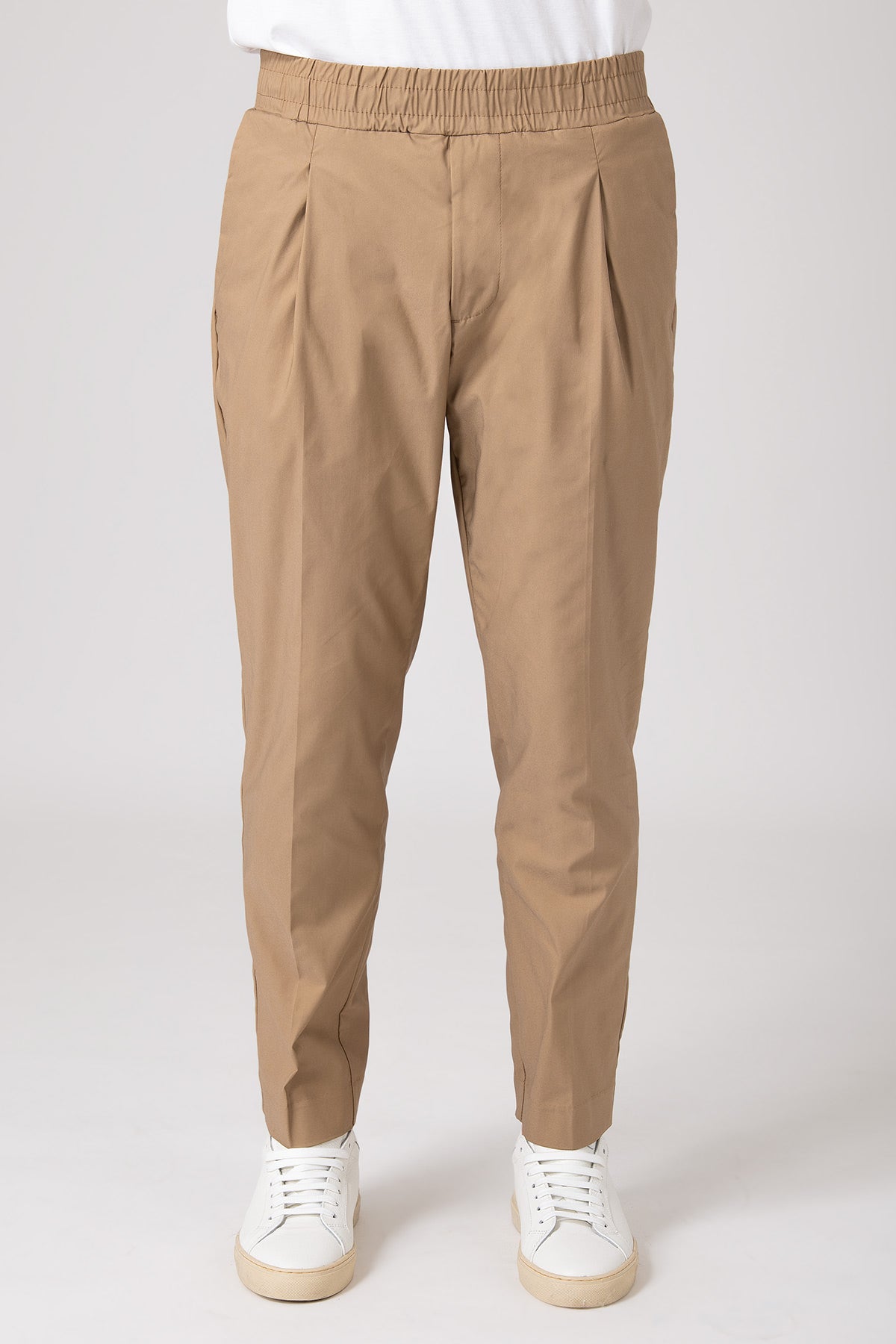 Man wearing beige carrot pants with elastic waist front view