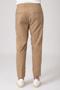 Man wearing beige carrot pants with elastic waist and back pockets, back view