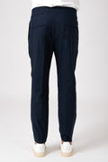 Man wearing blue carrot pants with elastic waist back view
