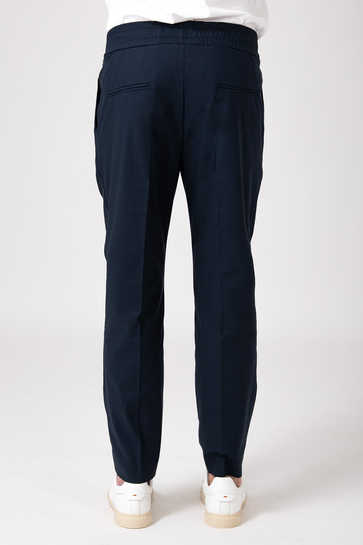 Man wearing blue carrot pants with elastic waist back view