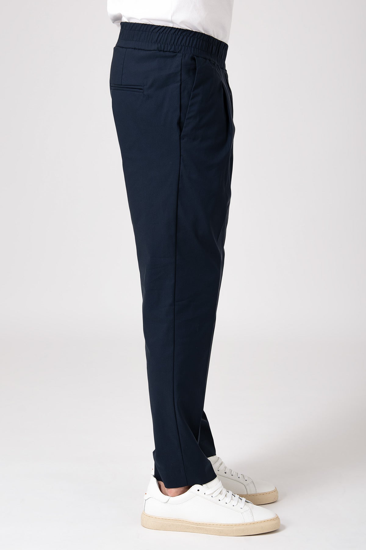 Man wearing navy blue carrot pants with elastic waist left side view
