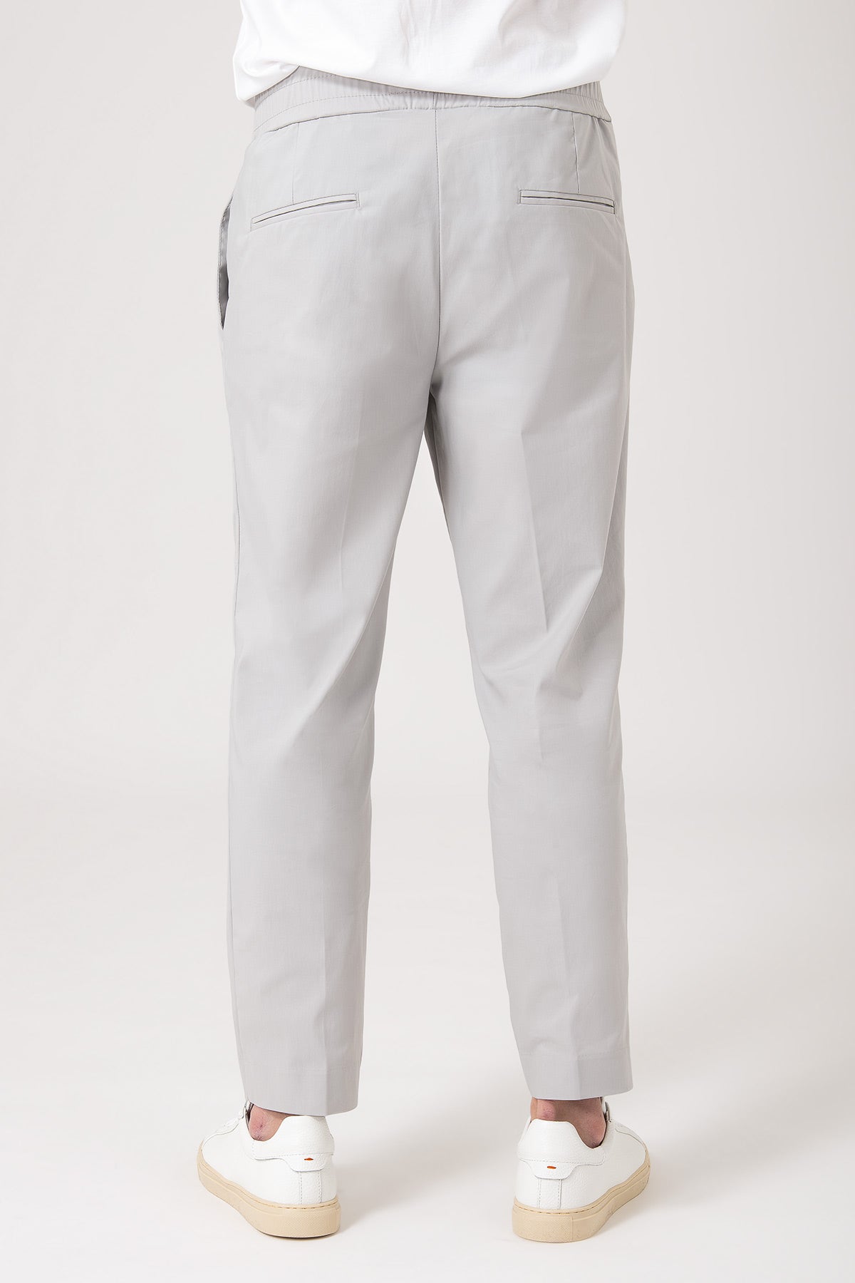 Man wearing grey carrot pants with elastic waist back view