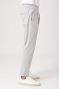 Person wearing gray carrot pants with elastic waistband side view