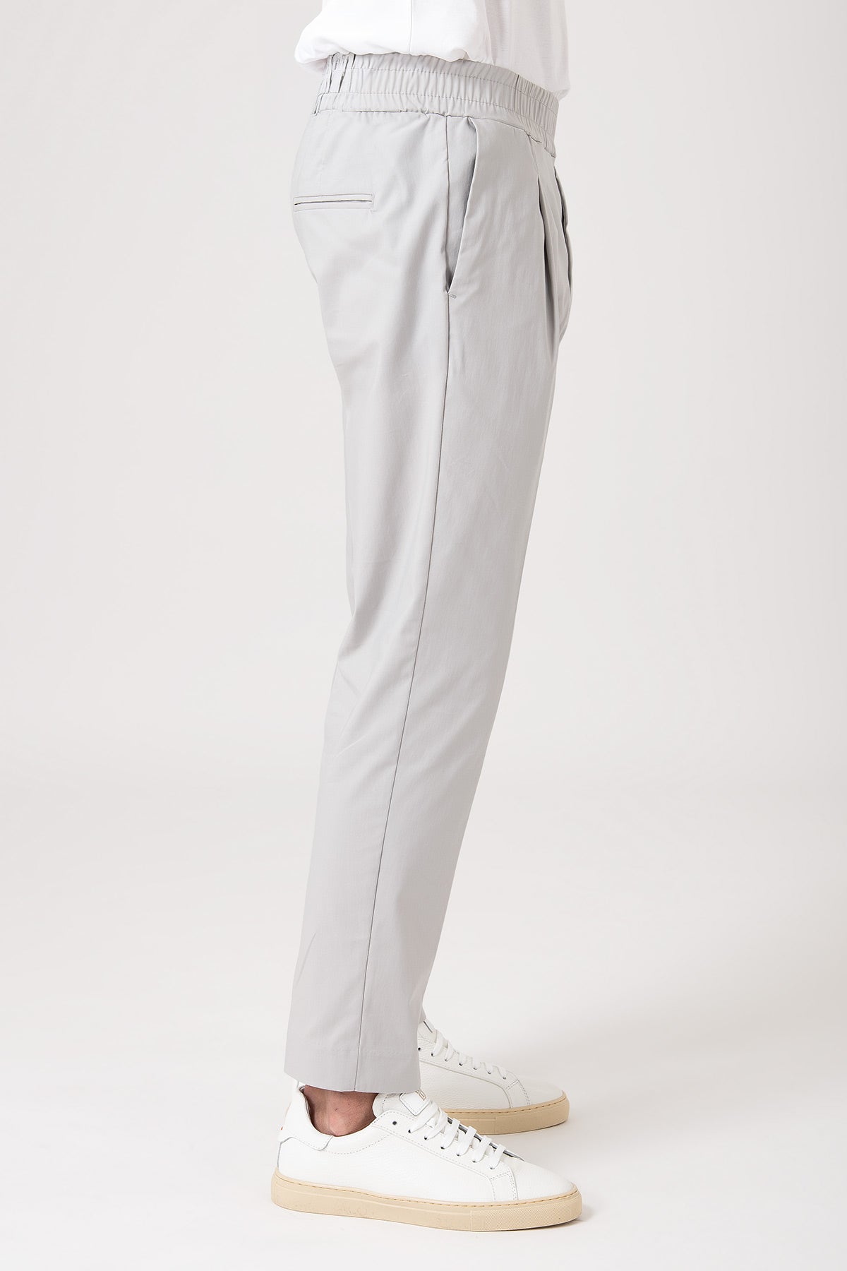 Person wearing gray carrot pants with elastic waistband side view