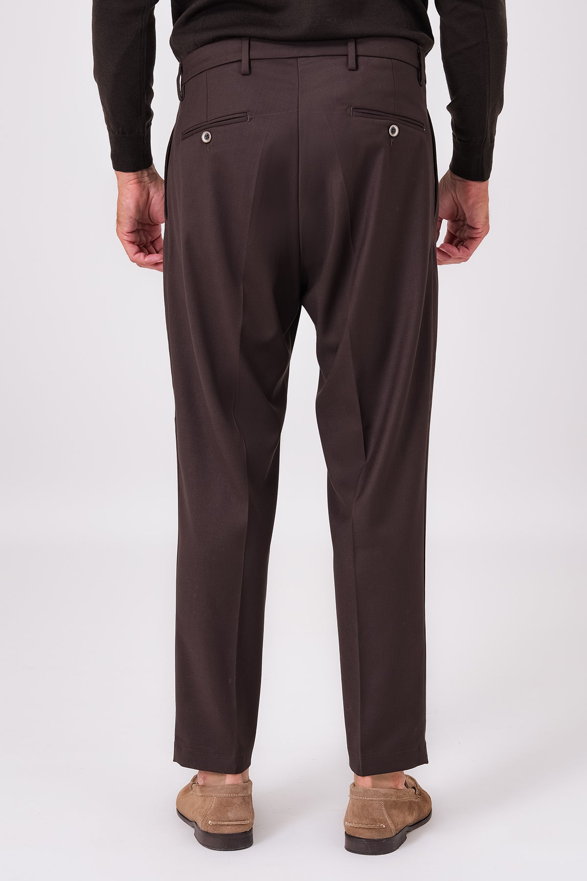 Rear view of dark brown trousers on a model with buttoned jet pockets