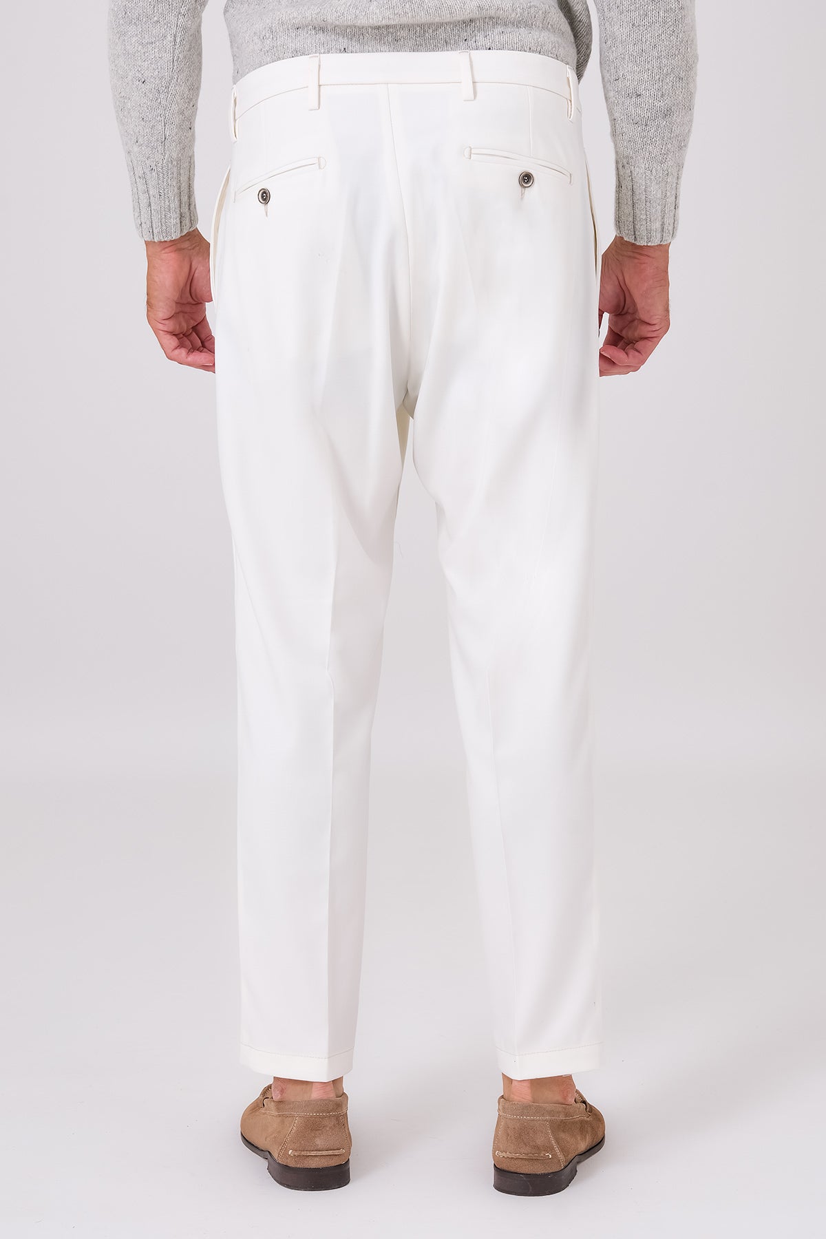 Rear view of cream trousers on a model, with welt pockets and buttons