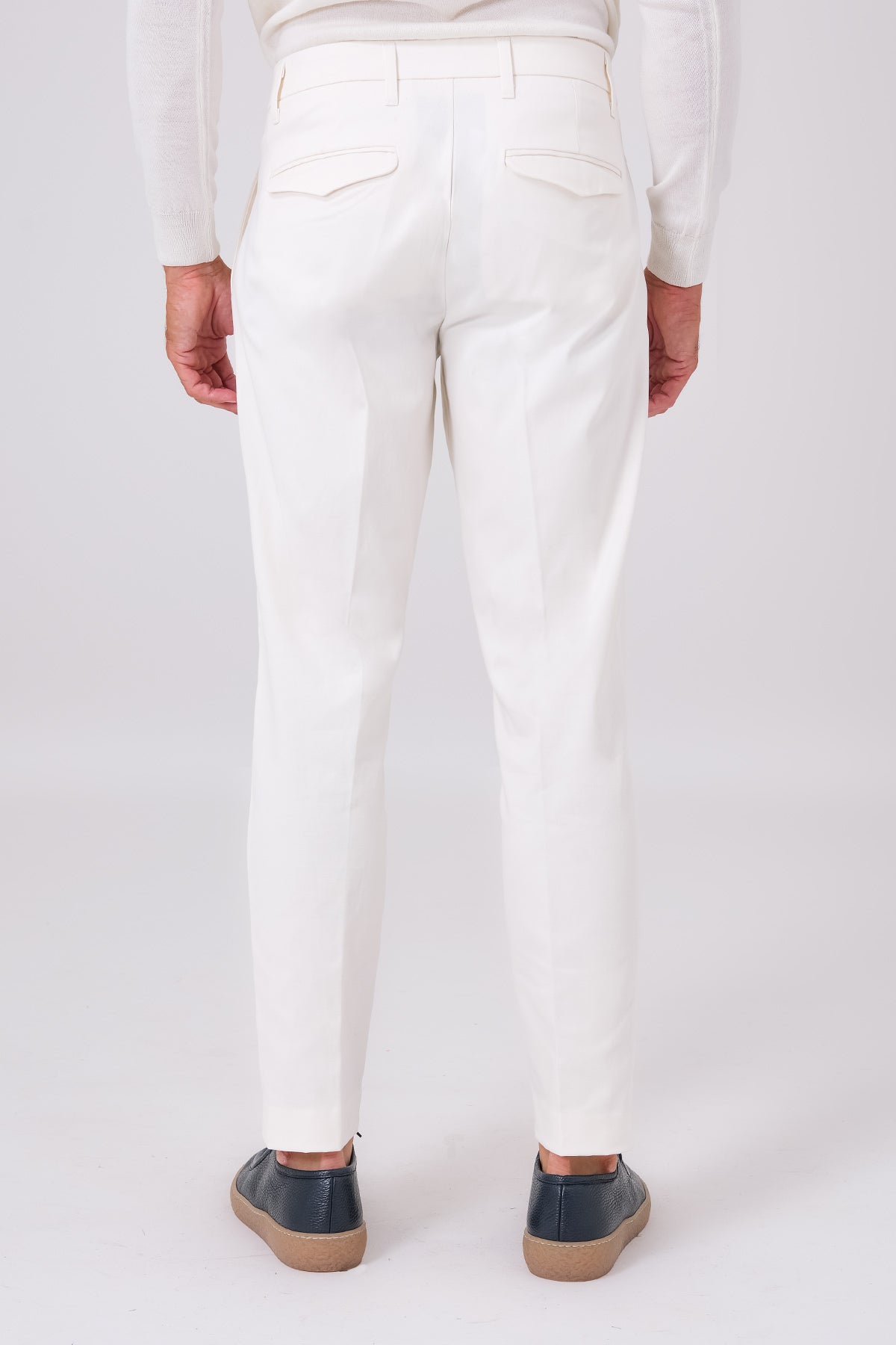 Rear view of cream pleated trousers on a model