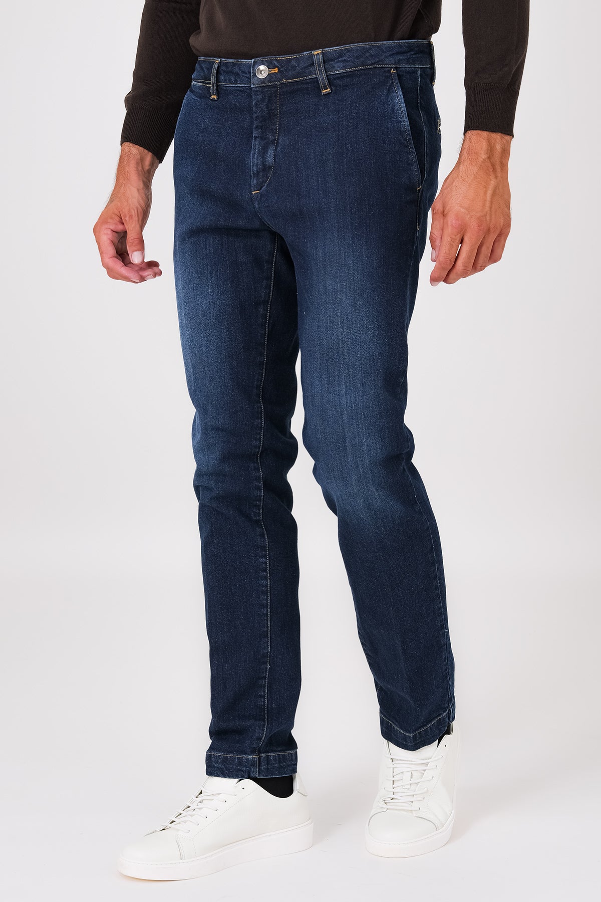 Front view of dark denim trousers with slant pockets on a model
