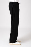 Uomo che indossa un pantalone largo nero fluido in visione laterale con scarpe bianche