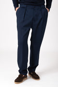 Man wearing blue wool French pence trousers with hands in pockets front view