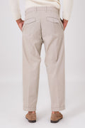 Vista posteriore del pantalone color mastice indossato, con tasche a filetto e fondo con risvolto