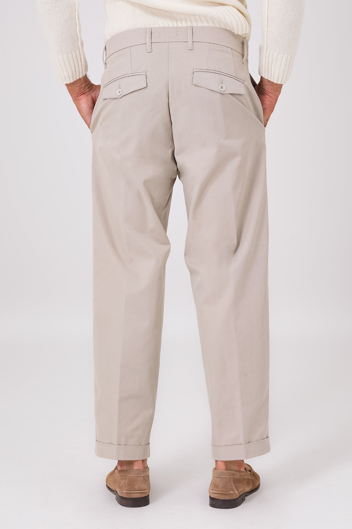Vista posteriore del pantalone color mastice indossato, con tasche a filetto e fondo con risvolto