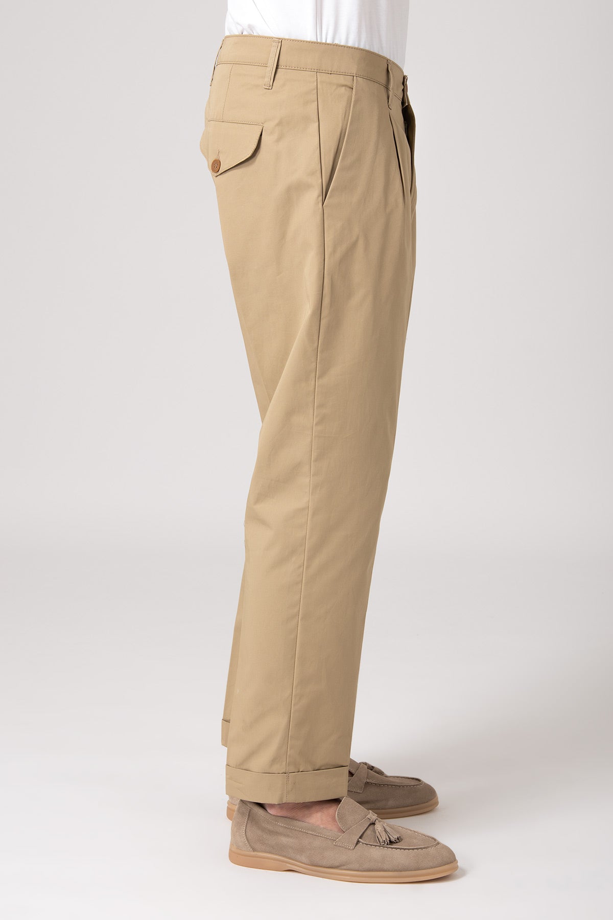 Man in side view wearing beige high-waisted pleated trousers
